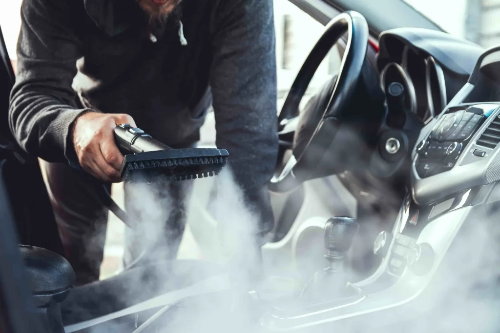 Car detailing technician using special pet hair removal tools on seats carpets and floor mats